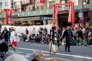 tall man in "tengu" costume, followed by a priestess