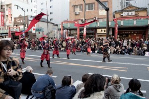 parade members in various forms of armor, led by a samurai in full battle gear