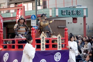 two men on float in Japanese armor, waving to the crowd